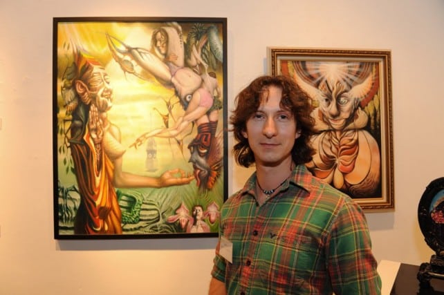 Cody smiling with his paintings.